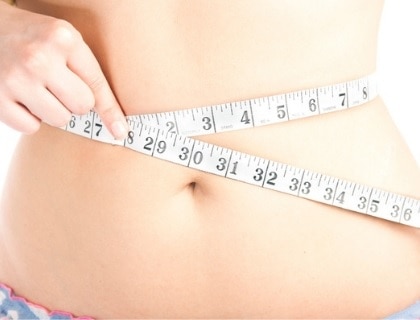 Woman measuring her belly with tape measure